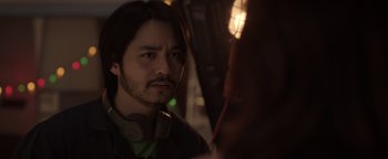 Movie still from “Kaleidoscope” (2023), directed by Mairzee Almas – A person wearing headphones; Close Up shot, Over the shoulder angle