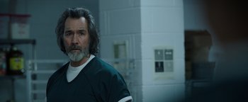 Movie still from “Kaleidoscope” (2023), directed by Mairzee Almas – A man with long hair and a beard standing in a room; Close Up shot, Over the shoulder angle