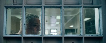 Movie still from “Kaleidoscope” (2023), directed by Mairzee Almas – An older man looking out of a jail cell; Close Up shot, Low angle