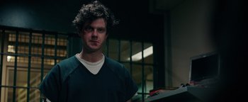 Movie still from “Kaleidoscope” (2023), directed by Mairzee Almas – A man with curly black hair standing in a room; Close Up shot, Over the shoulder angle
