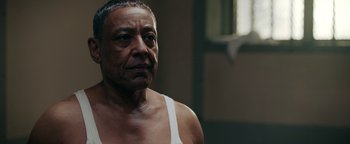 Movie still from “Kaleidoscope” (2023), directed by Mairzee Almas – An older man in a white tank top looking at the camera; Close Up shot, Low angle