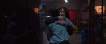 Movie still from “Kaleidoscope” (2023), directed by Mairzee Almas – A man and a woman hugging in a dark room; Medium shot, Over the shoulder angle