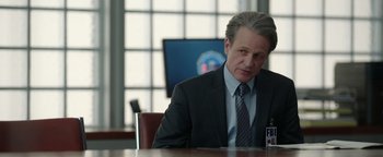 Movie still from “Kaleidoscope” (2023), directed by Mairzee Almas – A man sitting at a table in front of a computer monitor; Close Up shot, Over the shoulder angle