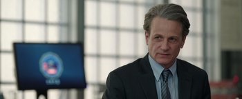 Movie still from “Kaleidoscope” (2023), directed by Mairzee Almas – A person wearing a suit and tie; Close Up shot, Over the shoulder angle