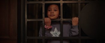 Movie still from “Kaleidoscope” (2023), directed by Mairzee Almas – A young girl standing behind a metal fence; Close Up shot, High angle