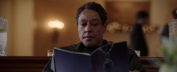 Movie still from “Kaleidoscope” (2023), directed by Mairzee Almas – A man sitting in front of an open book; Close Up shot, Over the shoulder angle