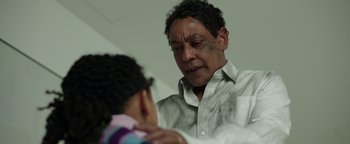 Movie still from “Kaleidoscope” (2023), directed by Mairzee Almas – An older man is looking in the mirror while a younger man looks on; Close Up shot, Over the shoulder angle