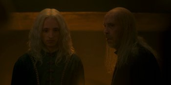 Movie still from “House of the Dragon” (2022), created by George R.R. Martin – Two men standing next to each other in a dimly - lit room; Close Up shot, Low angle