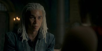 Movie still from “House of the Dragon” (2022), created by George R.R. Martin – A man with white dreadlocks is sitting in a dark room; Close Up shot, Over the shoulder angle