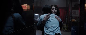 Movie still from “Kaleidoscope” (2023), directed by Mairzee Almas – Two people hugging each other in front of a mirror; Medium shot, Over the shoulder angle