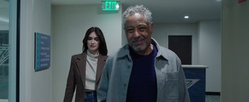 Movie still from “Kaleidoscope” (2023), directed by Mairzee Almas – A man and a woman standing next to each other in front of an exit sign; Medium shot, Over the shoulder angle