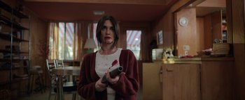 Movie still from “Kaleidoscope” (2023), directed by Mairzee Almas – A woman holding a video game controller in a living room; Medium shot, Over the shoulder angle