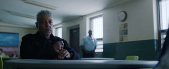Movie still from “Kaleidoscope” (2023), directed by Mairzee Almas – A man sitting at a table in front of two police officers; Medium shot, Over the shoulder angle
