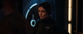 Movie still from “Kaleidoscope” (2023), directed by Mairzee Almas – A woman in black jacket standing next to a neon sign; Close Up shot, Over the shoulder angle