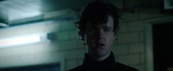 Movie still from “Kaleidoscope” (2023), directed by Mairzee Almas – A man with curly black hair standing in front of a brick wall; Close Up shot, Low angle