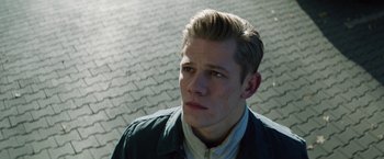 Movie still from “Kidnapping Stella” (2019), directed by Thomas Sieben – A young man is looking into the distance while standing on the sidewalk; Close Up shot, High angle