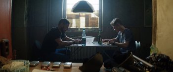 Movie still from “Kidnapping Stella” (2019), directed by Thomas Sieben – Two men are sitting at a table with food; Medium shot, Low angle