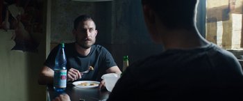 Movie still from “Kidnapping Stella” (2019), directed by Thomas Sieben – A man sitting at a table with a plate of food; Close Up shot, Over the shoulder angle