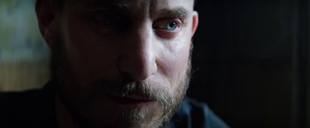 Movie still from “Kidnapping Stella” (2019), directed by Thomas Sieben – A man with a beard and blue eyes; Close Up shot, Over the shoulder angle