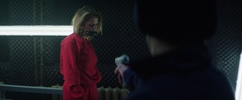 Movie still from “Kidnapping Stella” (2019), directed by Thomas Sieben – A woman in a red dress holding a cell phone in front of a mirror; Medium shot, Over the shoulder angle