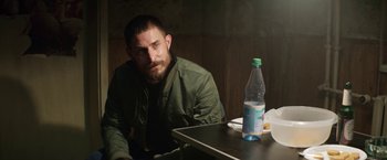 Movie still from “Kidnapping Stella” (2019), directed by Thomas Sieben – A man sitting at a table with a bottle of water; Medium shot, Over the shoulder angle