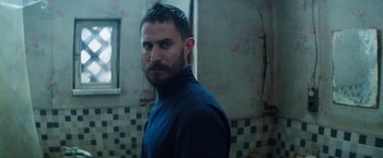 Movie still from “Kidnapping Stella” (2019), directed by Thomas Sieben – A man with a goatee standing next to a wall; Close Up shot, Low angle