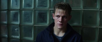 Movie still from “Kidnapping Stella” (2019), directed by Thomas Sieben – A young man in a black jacket is looking at the camera; Close Up shot, Over the shoulder angle