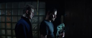 Movie still from “Kidnapping Stella” (2019), directed by Thomas Sieben – Two men standing next to each other in a dark room; Medium shot, Low angle