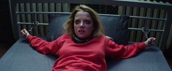 Movie still from “Kidnapping Stella” (2019), directed by Thomas Sieben – A woman in a red shirt laying on a couch; Medium shot, Overhead angle