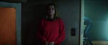Movie still from “Kidnapping Stella” (2019), directed by Thomas Sieben – A woman in a red shirt is standing in a dark room; Medium shot, High angle