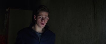 Movie still from “Kidnapping Stella” (2019), directed by Thomas Sieben – A young man in a dark room looking at the camera; Close Up shot, Low angle