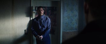 Movie still from “Kidnapping Stella” (2019), directed by Thomas Sieben – A man standing in a dark room holding a remote control; Medium shot, Low angle