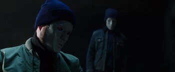 Movie still from “Kidnapping Stella” (2019), directed by Thomas Sieben – Two people in a dark room with one of them wearing a blue hat; Close Up shot, Over the shoulder angle