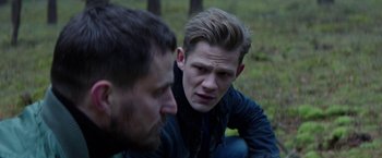 Movie still from “Kidnapping Stella” (2019), directed by Thomas Sieben – Two men sitting on the ground in the grass; Close Up shot, Over the shoulder angle