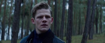 Movie still from “Kidnapping Stella” (2019), directed by Thomas Sieben – A man in a black jacket in the woods; Close Up shot, Over the shoulder angle