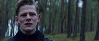 Movie still from “Kidnapping Stella” (2019), directed by Thomas Sieben – A man in a black jacket is standing in a forest; Close Up shot, Low angle