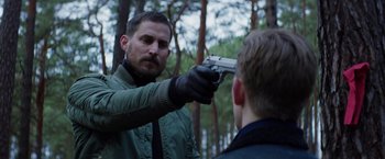 Movie still from “Kidnapping Stella” (2019), directed by Thomas Sieben – A man holding a gun up to a man's face; Medium shot, Over the shoulder angle
