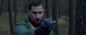 Movie still from “Kidnapping Stella” (2019), directed by Thomas Sieben – A person holding a gun in the woods; Close Up shot, Over the shoulder angle