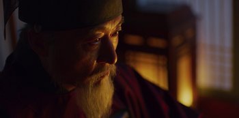 Movie still from “Kingdom” (2019), created by Eun-hee Kim – An old man with a beard is looking at the camera; Close Up shot, Over the shoulder angle