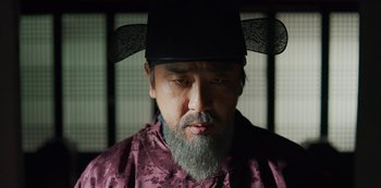 Movie still from “Kingdom” (2019), created by Eun-hee Kim – An older man with a beard and a black hat; Close Up shot, Low angle