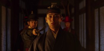 Movie still from “Kingdom” (2019), created by Eun-hee Kim – A young man in traditional japanese garb holding an axe; Medium shot, Low angle