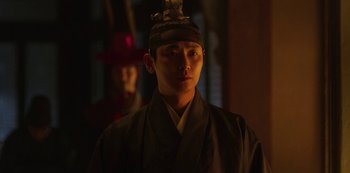 Movie still from “Kingdom” (2019), created by Eun-hee Kim – A man wearing a black hat and a black robe; Close Up shot, Low angle