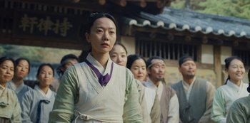 Movie still from “Kingdom” (2019), created by Eun-hee Kim – A group of people standing next to each other in front of a building; Medium shot, Over the shoulder angle