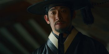 Movie still from “Kingdom” (2019), created by Eun-hee Kim – A person wearing a hat; Close Up shot, Low angle