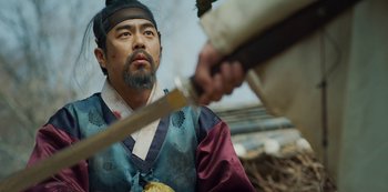 Movie still from “Kingdom” (2019), created by Eun-hee Kim – A man in a blue and black outfit holding a sword; Medium shot, Over the shoulder angle