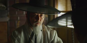 Movie still from “Kingdom” (2019), created by Eun-hee Kim – A man with a long white beard wearing a black hat; Close Up shot, Low angle