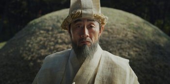 Movie still from “Kingdom” (2019), created by Eun-hee Kim – An old man with a long beard wearing a hat; Close Up shot, Low angle
