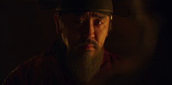 Movie still from “Kingdom” (2019), created by Eun-hee Kim – A man with a beard wearing a hat; Close Up shot, Low angle