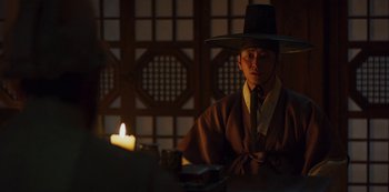 Movie still from “Kingdom” (2019), created by Eun-hee Kim – A man wearing a black hat and a brown robe; Medium shot, Over the shoulder angle
