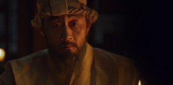 Movie still from “Kingdom” (2019), created by Eun-hee Kim – A person with a beard wearing a hat; Close Up shot, Low angle